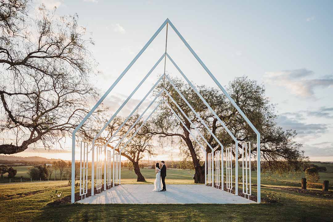 Newlyweds practice their first dance in the peppercorn chapel at Burnham Grove with the golden sunset behind them